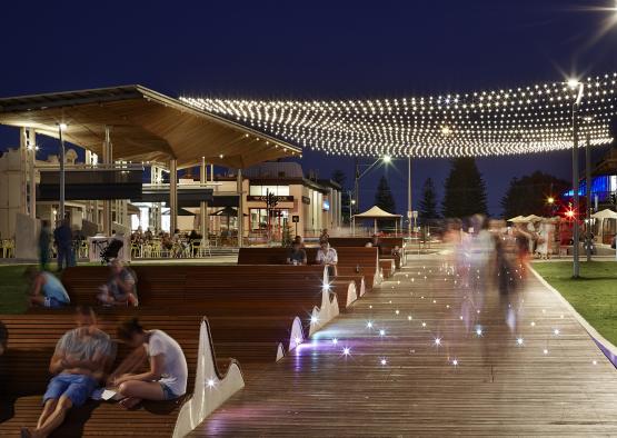 people sitting on a wooden bench with lights on the ceiling