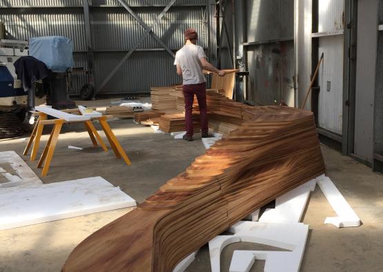 a man standing next to a large piece of wood