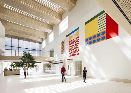 people in a building with a large white wall and a couple of people walking