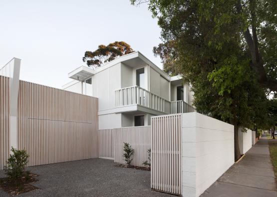 a white house with a fence and trees