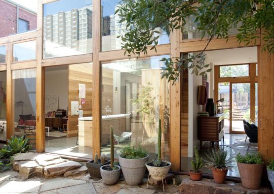 a glass wall of a house with a group of potted plants