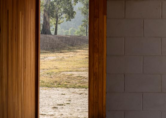 a wooden doorway with a view of a field and trees