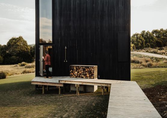 a black building with a wood stack in the front