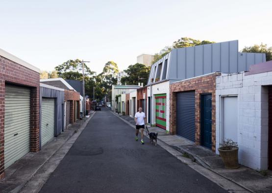 a man walking a dog on a street with garages