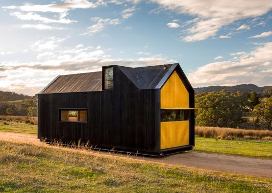 a black and yellow house on a dirt road