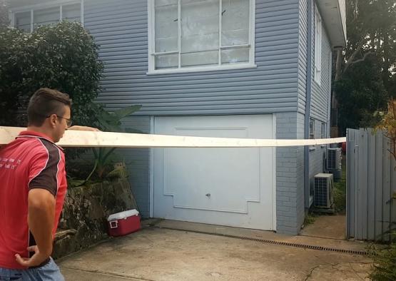 a man holding a long wooden plank in front of a house