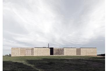 a long brick wall with a grassy field and a blue sky