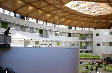 a large building with green chairs and a large white wall